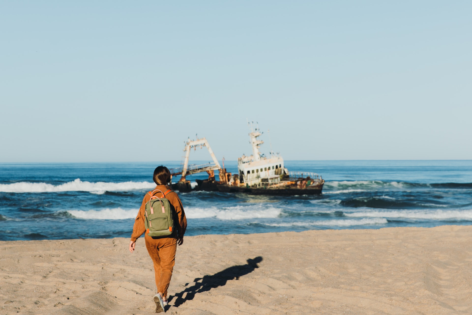 Female backpacker exploring the Skeleton coast with a shipwreck just offshore